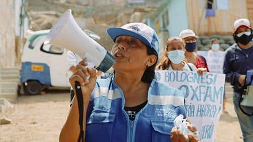 Mujer con megafono y chaleco azul por la calle