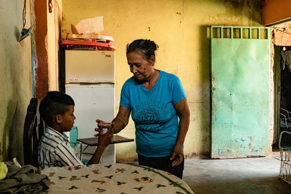 Mujer mayor entregando alimento a niño en una cocina