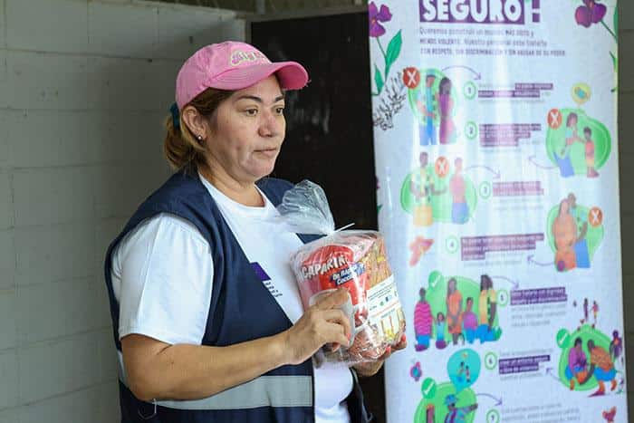 Mujer mostrando víveres hacia un grupo de personas